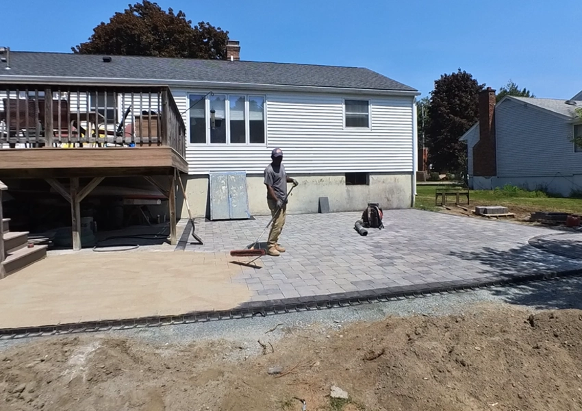 Crew finishing the paver patio installation in Framingham Massachusetts M Coelho Group